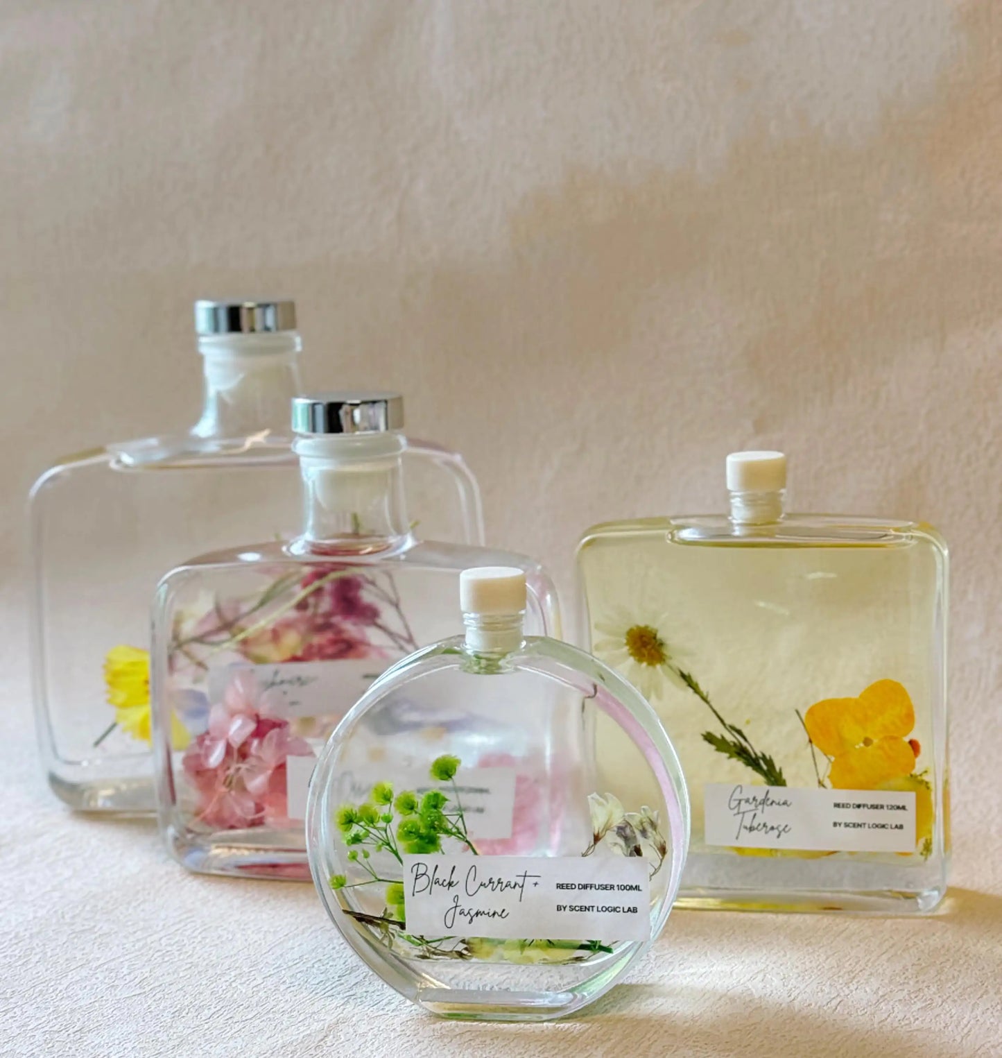 Set of glass perfume bottles with floral labels on a neutral background